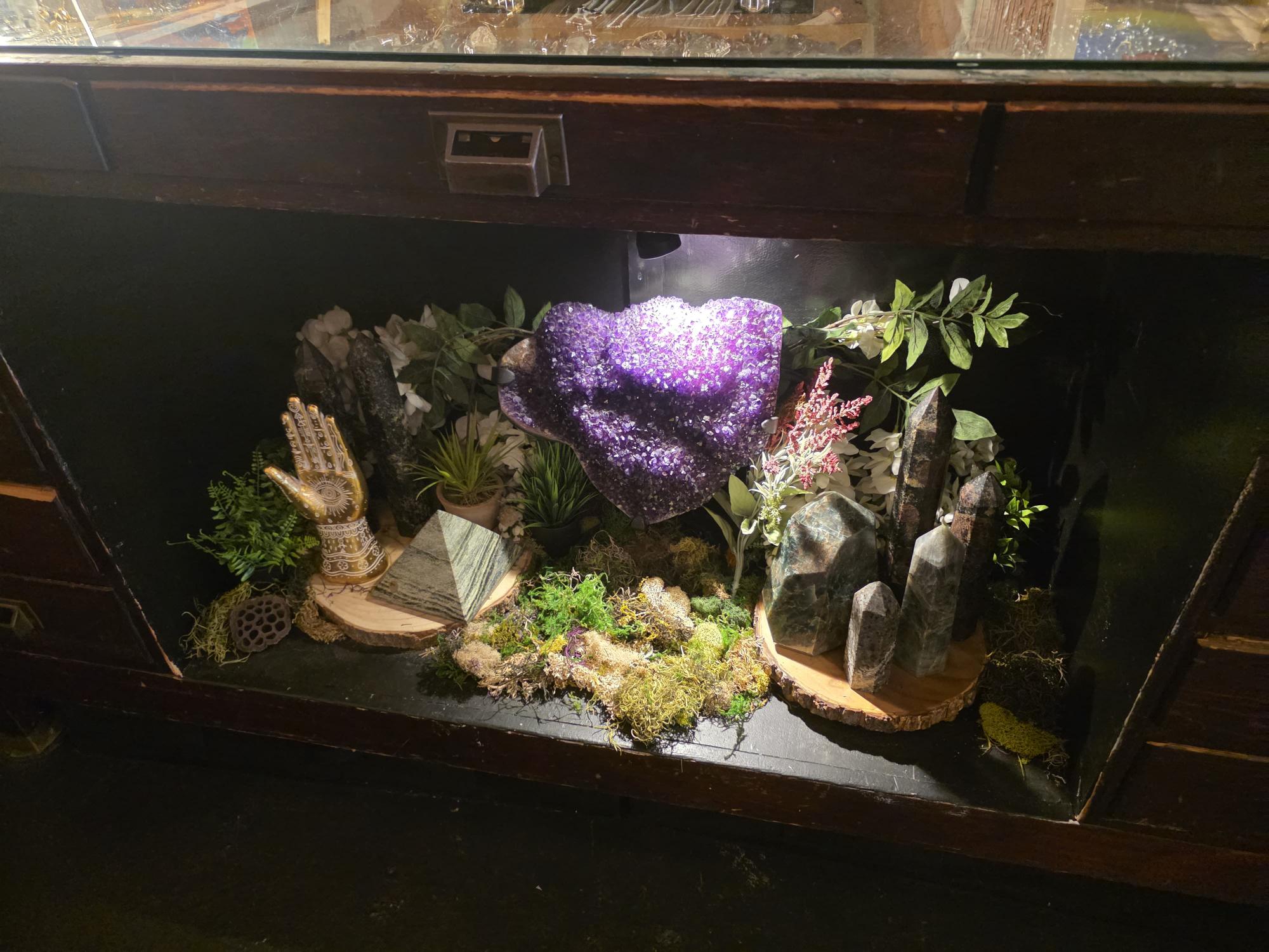 A glass case display featuring an illuminated amethyst geode