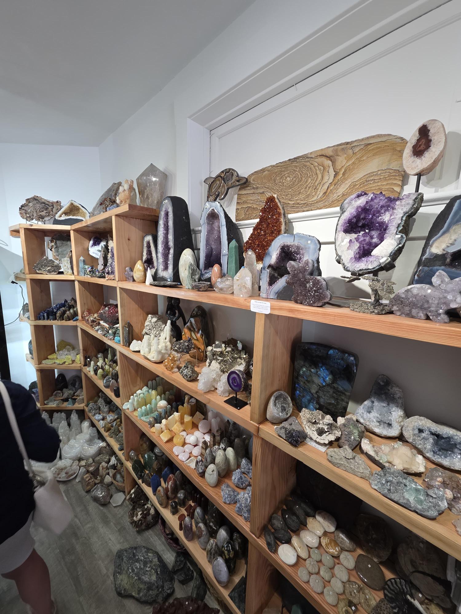 A wall of amethyst geodes and crystals on display